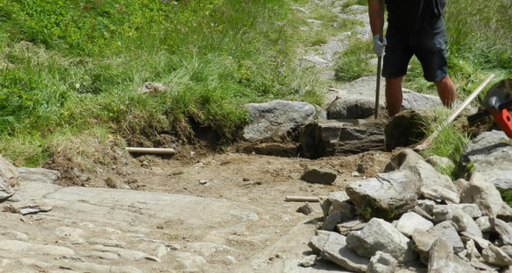 Die Steine aus der bestehenden Strasse wurden wieder verwendet. Ein Wassergraben auf der Hangseite dient der Entwässerung. Die Steine aus der bestehenden Strasse wurden wieder verwendet. Ein Wassergraben auf der Hangseite dient der Entwässerung.